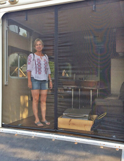 Summer-clad woman enjoying bug-free view from inside her toy hauler garage through ToyHaulerScreen ramp screen